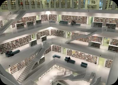 Uma biblioteca enorme composta por milhares de livros e vários lances de escadas.